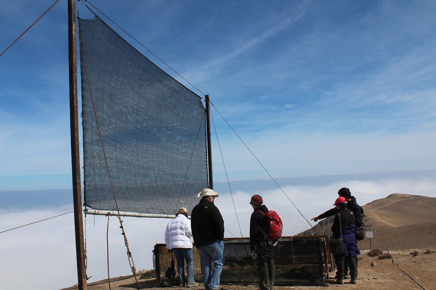 A large fog collector standing on a coastal ridge above the cloud layer in Chile