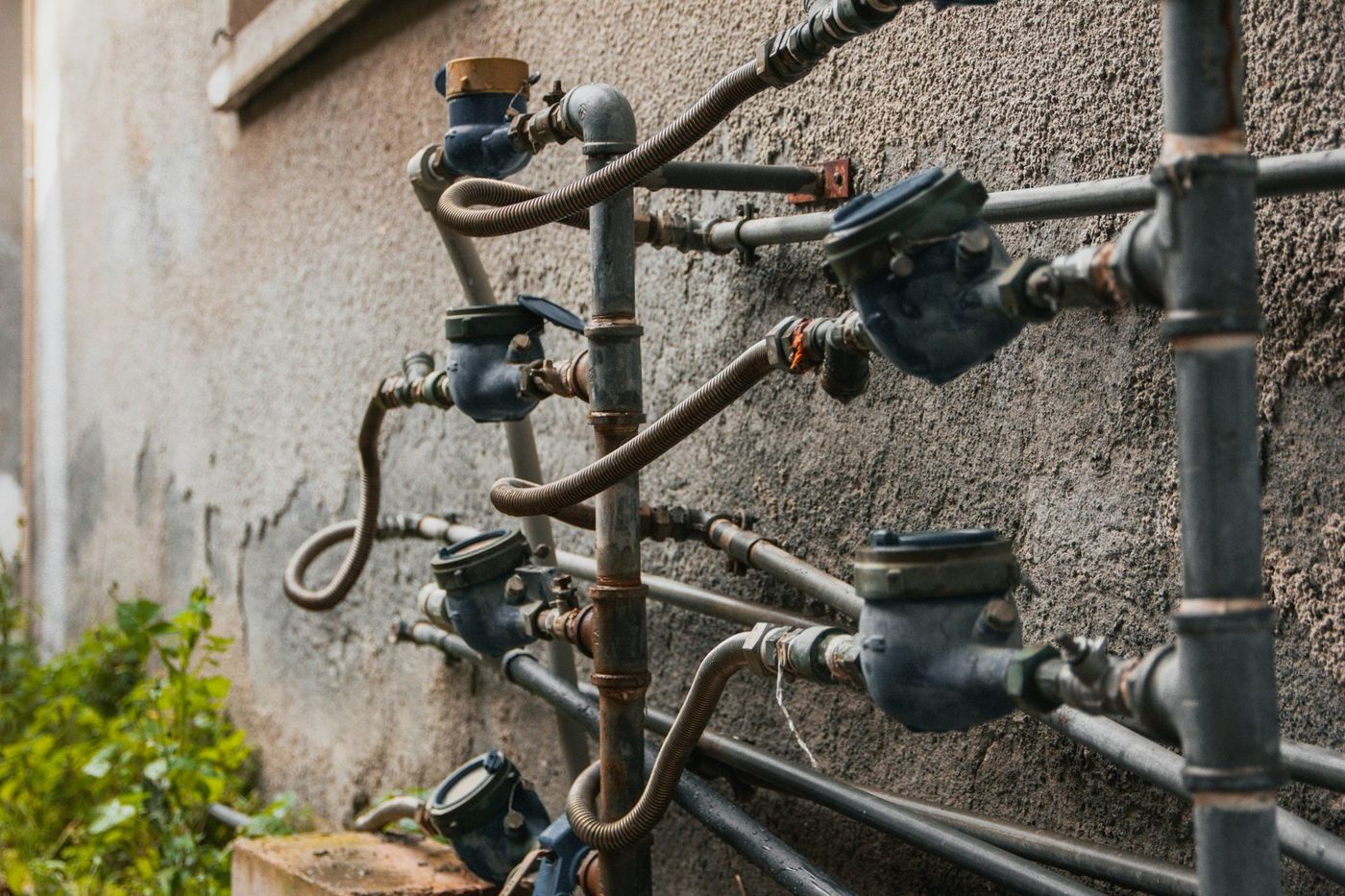 A bank of ageing water meters on the outside wall of a building
